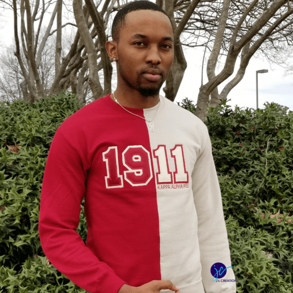A person stands outdoors with trees in the background, wearing an Embroidered 1911 Kappa Alpha Psi Inspired Half and Half Crew Neck Unisex Sweatshirt.