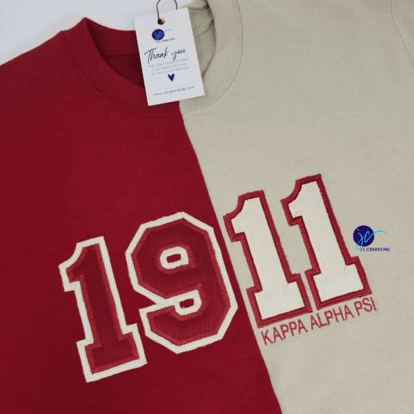 Two sweatshirts side by side with the number 1911 and the words "Kappa Alpha Psi" displayed on them. A thank you card with a logo is attached to the Embroidered 1911 Kappa Alpha Psi Inspired Half and Half Crew Neck Unisex Sweatshirt.