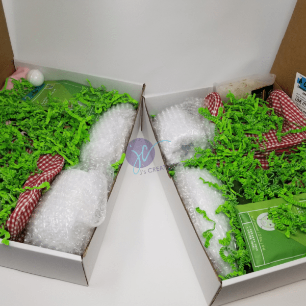 Two open Mother's Day Gift Boxes with various items inside, including bubble wrap, green shredded paper, and checkered fabric. The boxes are placed next to each other on a white background.