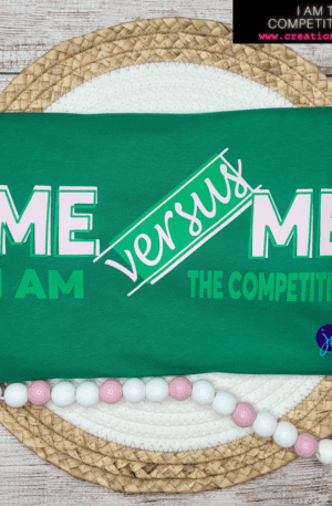 A green shirt that says " me versus i am the competition ".