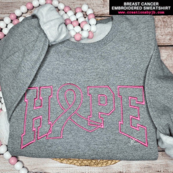 A gray sweatshirt with pink letters and breast cancer awareness ribbon.