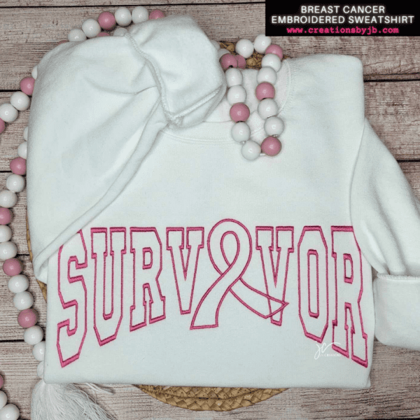 A white sweatshirt with pink lettering that says " survivor ".