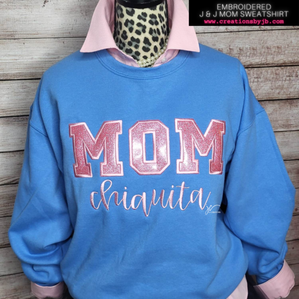 A blue sweatshirt with the word mom and a pink lettering.